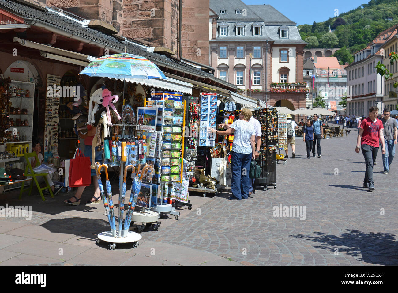 Touristen in Souvenirläden mit verschiedenen lokalen Trinkets am Marktplatz an einem sonnigen Tag in Heidelberg, Deutschland Stockfoto
