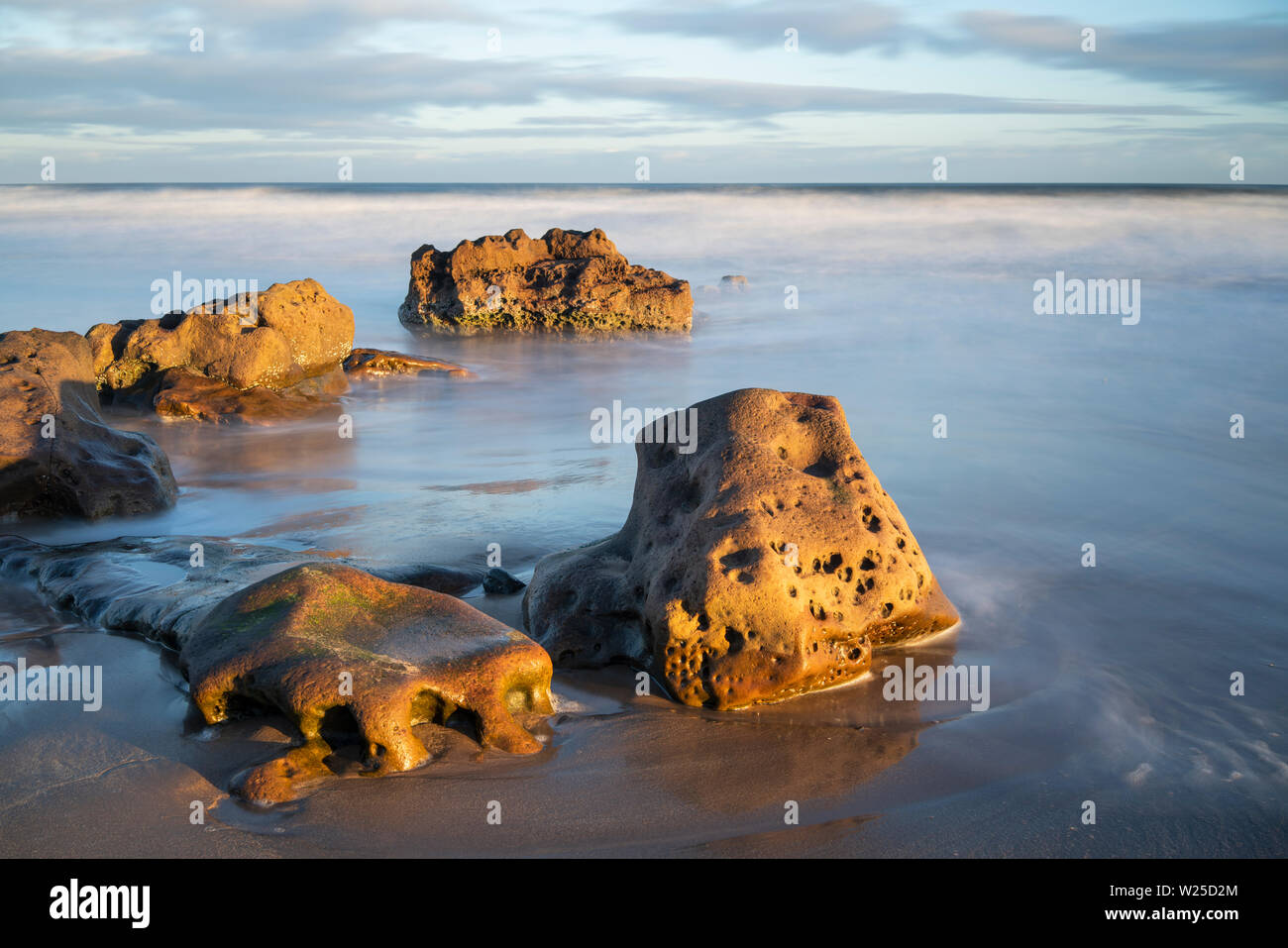 Erstes Licht auf Felsen auf cheswick Sands, Northumberland, England Stockfoto