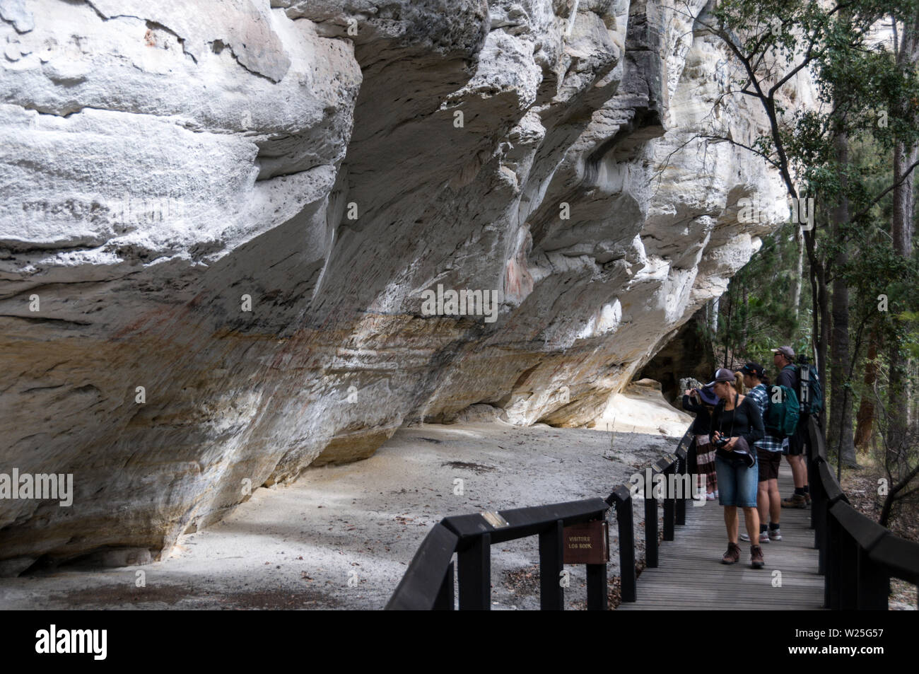 Besucher im gut erhaltenen Aboriginal Rock Art site Schablone, als die "Art Gallery" 3.650 Jahre alt auf dem weißen Sandsteinfelsen. Stockfoto