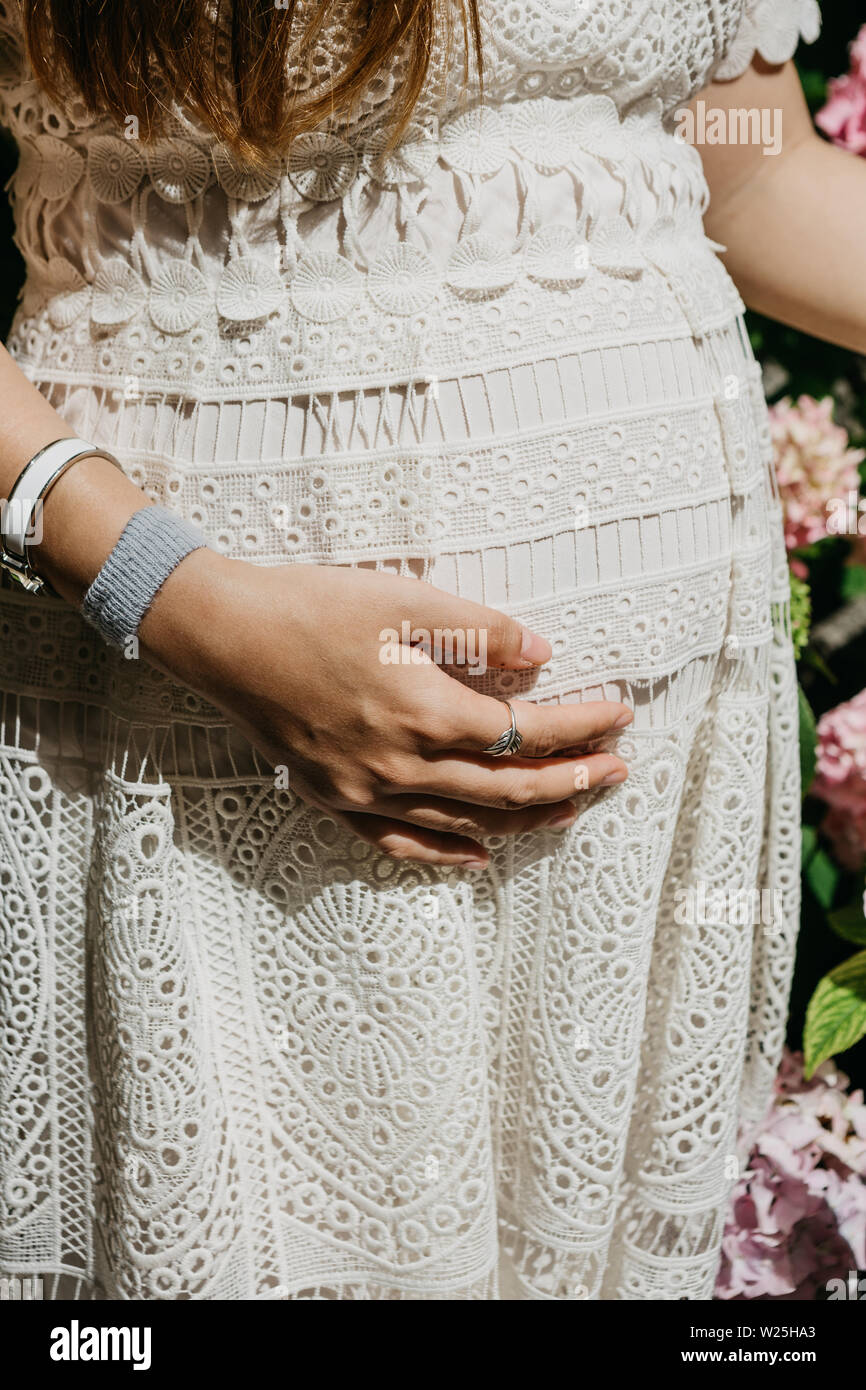 Nahaufnahme der schwangeren Frau mit der Hand über den Bauch. Warten auf die Geburt eines Kindes. Mütterliche Betreuung. Stockfoto
