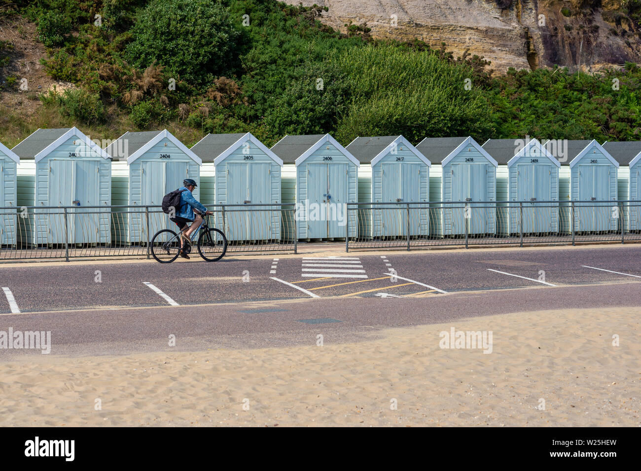 Radfahrer, Sky Blue Beach Hütten stehen in einer Reihe an der Promenade von Bournemouth, Dorset, Großbritannien Stockfoto
