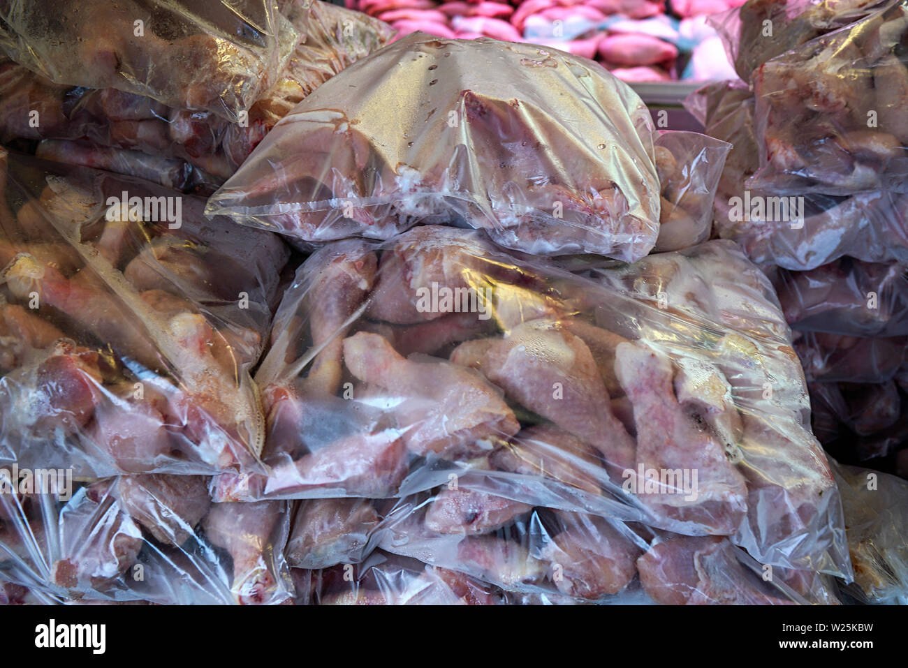 Rohes Fleisch und Geflügel - Hähnchen Schenkel - in Plastiktüten auf Anzeige an Metzgerei Fenster Stockfoto
