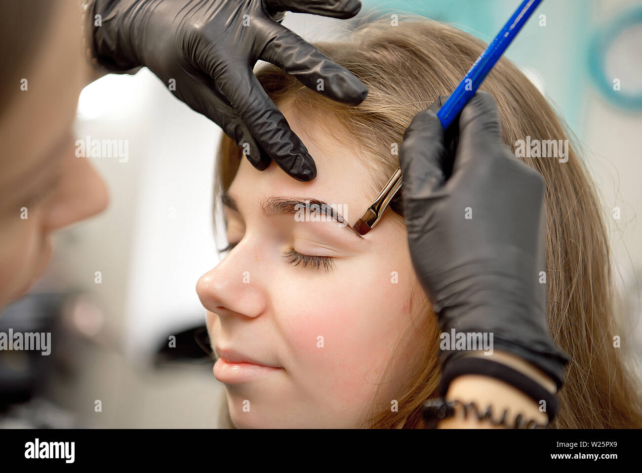 Schöne Frau Zeichnen einer Form der Augenbrauen mit kosmetischen Bürste. Make-up Artist Anwendung bis zu einem Modell Stockfoto