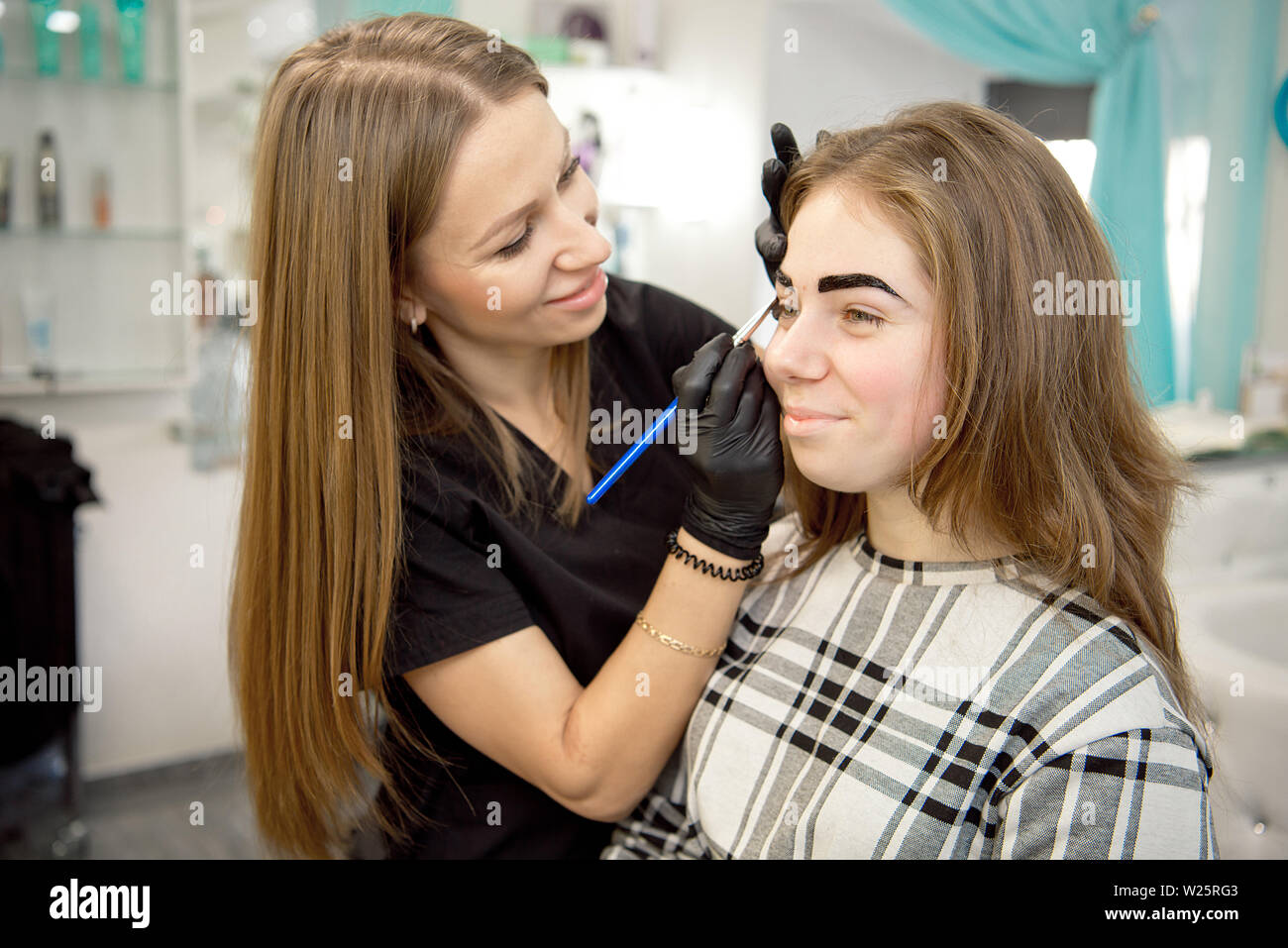 Make-up-Artist, professionelle Make-up einer jungen Frau in der Nähe des Spiegels in Beauty Studio. Stockfoto