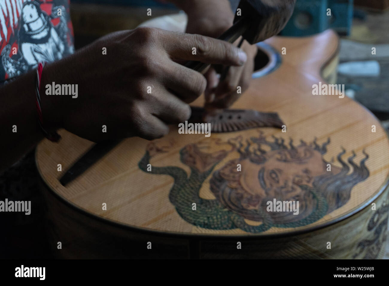 Eine Gitarre Handwerker ist Mess- und sicher ist es Präzision in einem hölzernen Gitarren Workshop in Guwang Dorf, Gianyar, Bali. Dies ist ein Geschnitzter Gitarre Stockfoto