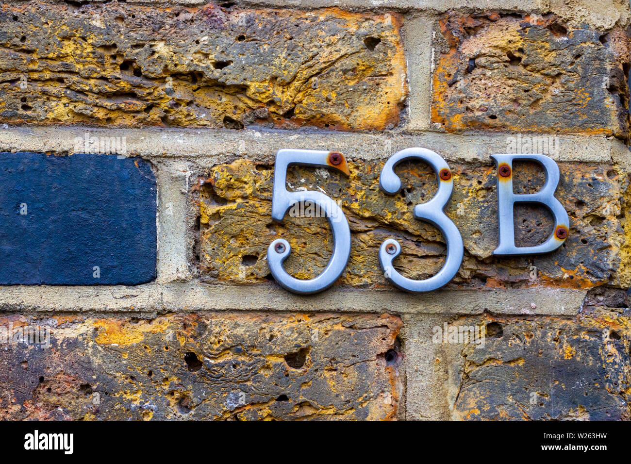 Haus Nummer 53 b mit der 53b in Metall Ziffern auf einer hölzernen Tür Stockfoto