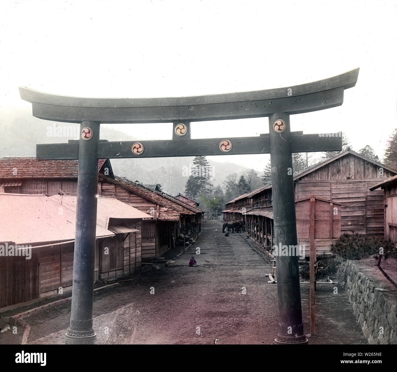 [1900s Japan - Heilige Torii-tor im Village] - ein broze Heilige torii Tor in einem Dorf in der Nähe der See Chuzenji. In der Rückseite einige Pferde gesehen werden kann. 20. Jahrhundert vintage Glas schieben. Stockfoto