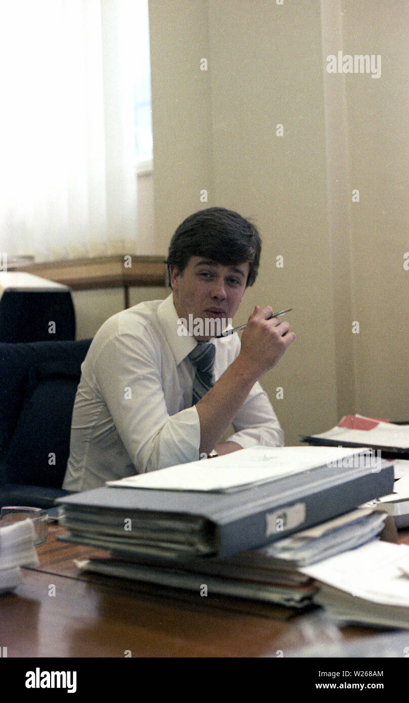 1970 s, historischen, ein Mann, Anfang der 30er Jahre, im Büro, am Schreibtisch, einem Unternehmen, Manager oder möglicherweise jemand in der Finanzabteilung oder ein Buchhalter, England, UK. Stockfoto