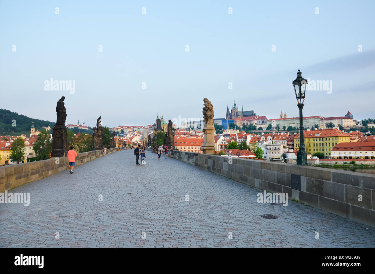 Prag, Tschechische Republik - 27. Juni 2019: Menschen zu Fuß auf der berühmten Karlsbrücke in der historischen Altstadt von der tschechischen Hauptstadt. In den frühen Morgenstunden bei Sonnenaufgang das Licht fotografiert. Gotische Wahrzeichen, Statuen. Stockfoto