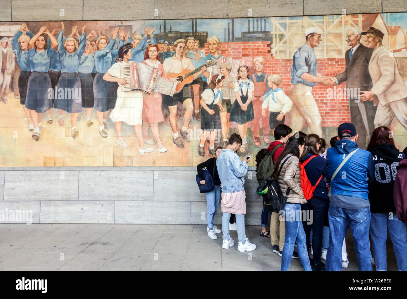 Gruppe von Touristen Bellow Sozialistischen Realismus Kunst aus der Zeit der kommunistischen deutschen Republik, Ministerium für Finanzen, Berlin Deutschland Berlin City People Stockfoto