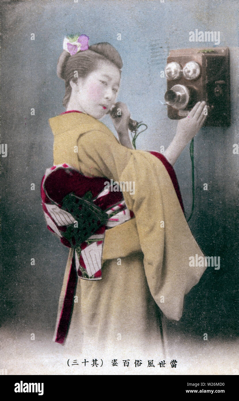 [1900s Japan - Japanische Frau mit Telefon] - Frau im Kimono und traditionellen haistyle ein Telefonanruf. Japan importiert seinen ersten Telefon 1877 (Meiji 10). 20. jahrhundert alte Ansichtskarte. Stockfoto