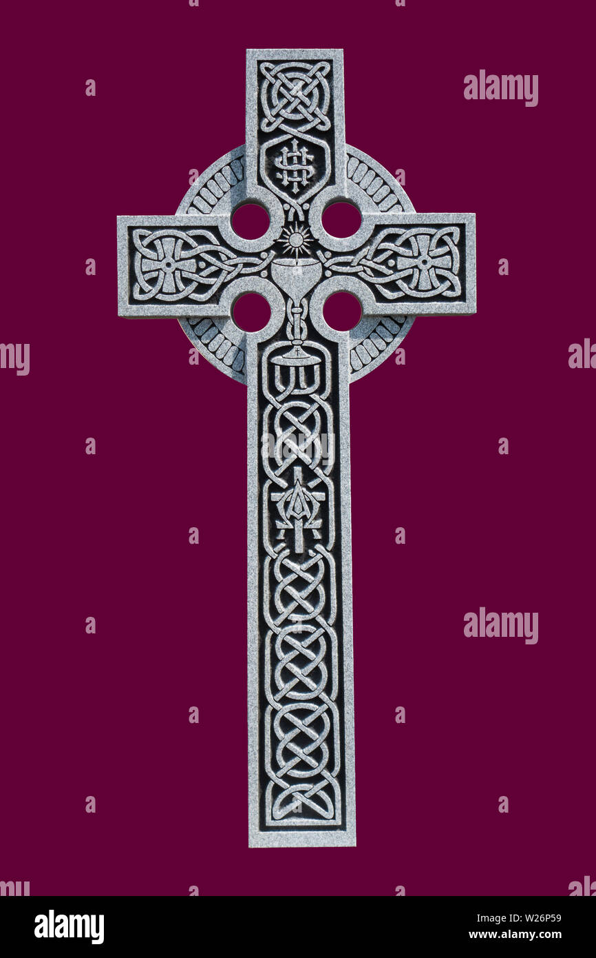 Eine reich verzierte Granit Celtic Cross aus dem Grab von einem römisch-katholischen Priester, die die keltischen Knoten Muster, einer Gemeinschaft, Kelch, und das IHS Symbol Stockfoto