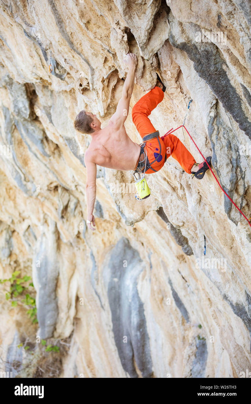 Kaukasischen jungen Mann klettern anspruchsvolle Strecke auf überhängenden Klippe Stockfoto