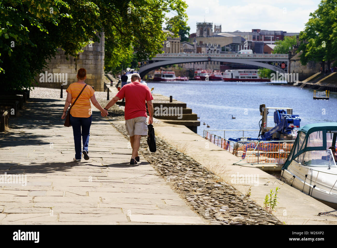 Beim Spaziergang am Fluss Ouse sind ein Mann und eine Frau Hand in Hand, Dame Judi Dench Walk, York, North Yorkshire, England, Großbritannien. Stockfoto