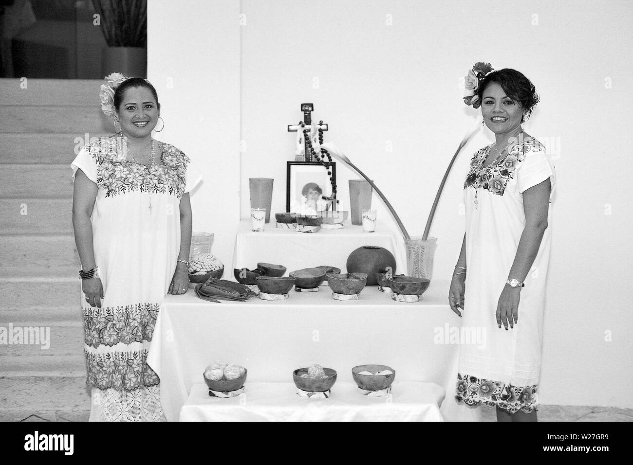 MERIDA, Yuc/MEXIKO-NOV 1ST, 2013: Hanal Pixan (Tag der Toten). Zwei Frauen in traditioneller Kleidung stellen neben einem Altar. BW-film Stockfoto