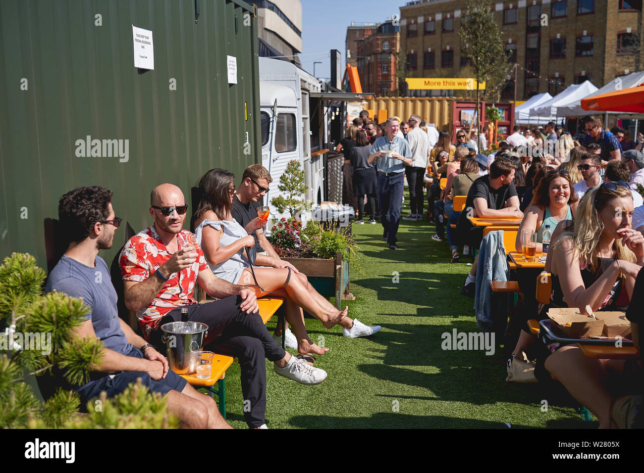 London, UK, 2019. Junge Menschen, die Getränke in Essig Hof, eine neue Straße Essen und Kunst Markt in der Nähe der London Bridge Station. Stockfoto