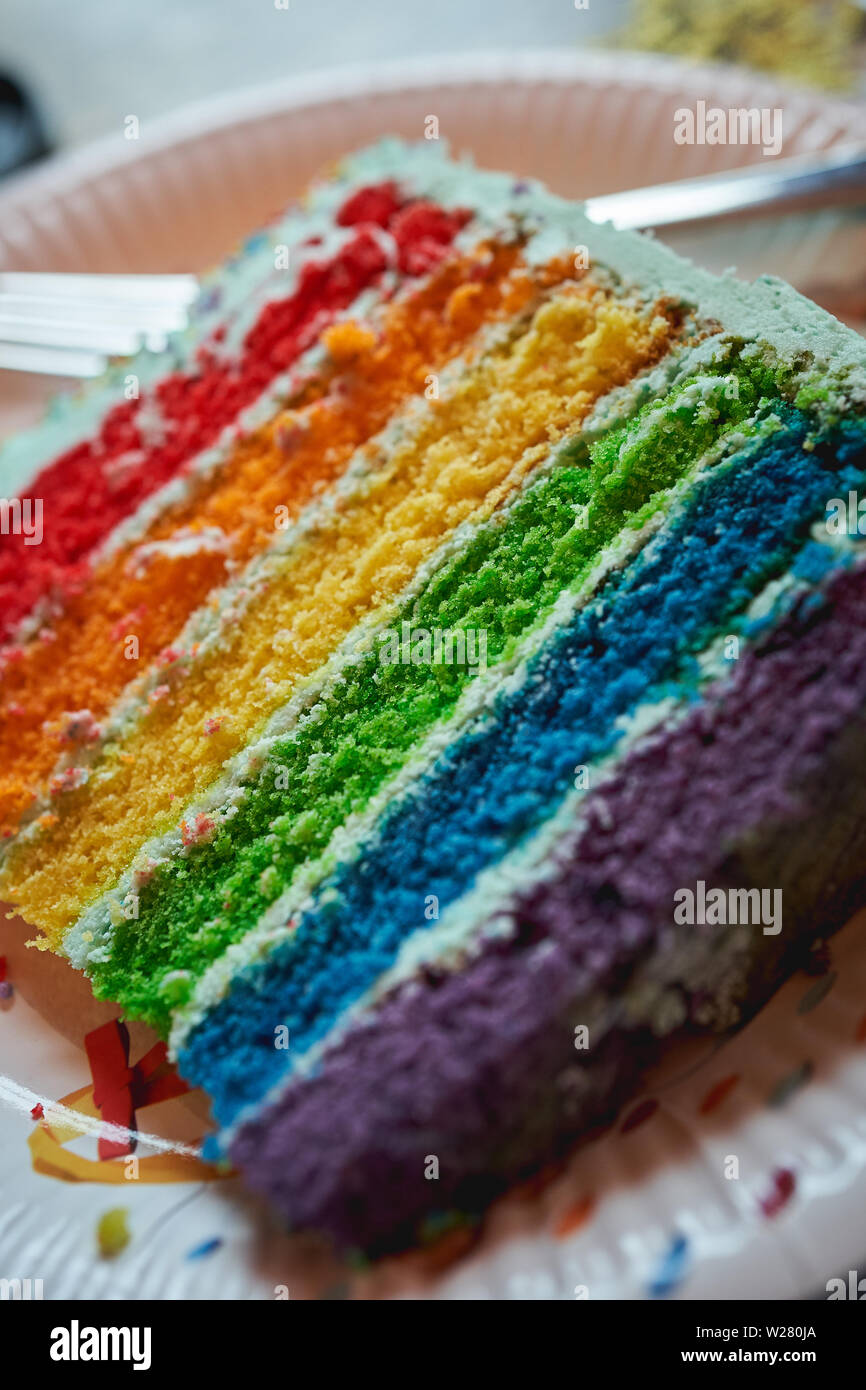 Nahaufnahme einer Scheibe einer rainbow Geburtstag Kuchen auf eine Platte. Hochformat. Stockfoto