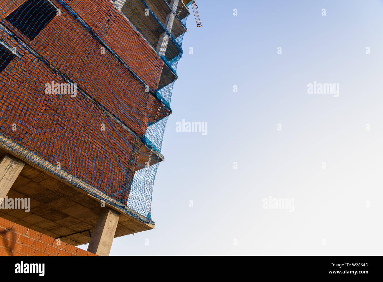 Gebäude im Bau mit Ziegelwänden und Schutznetze für Arbeitnehmer. Stockfoto