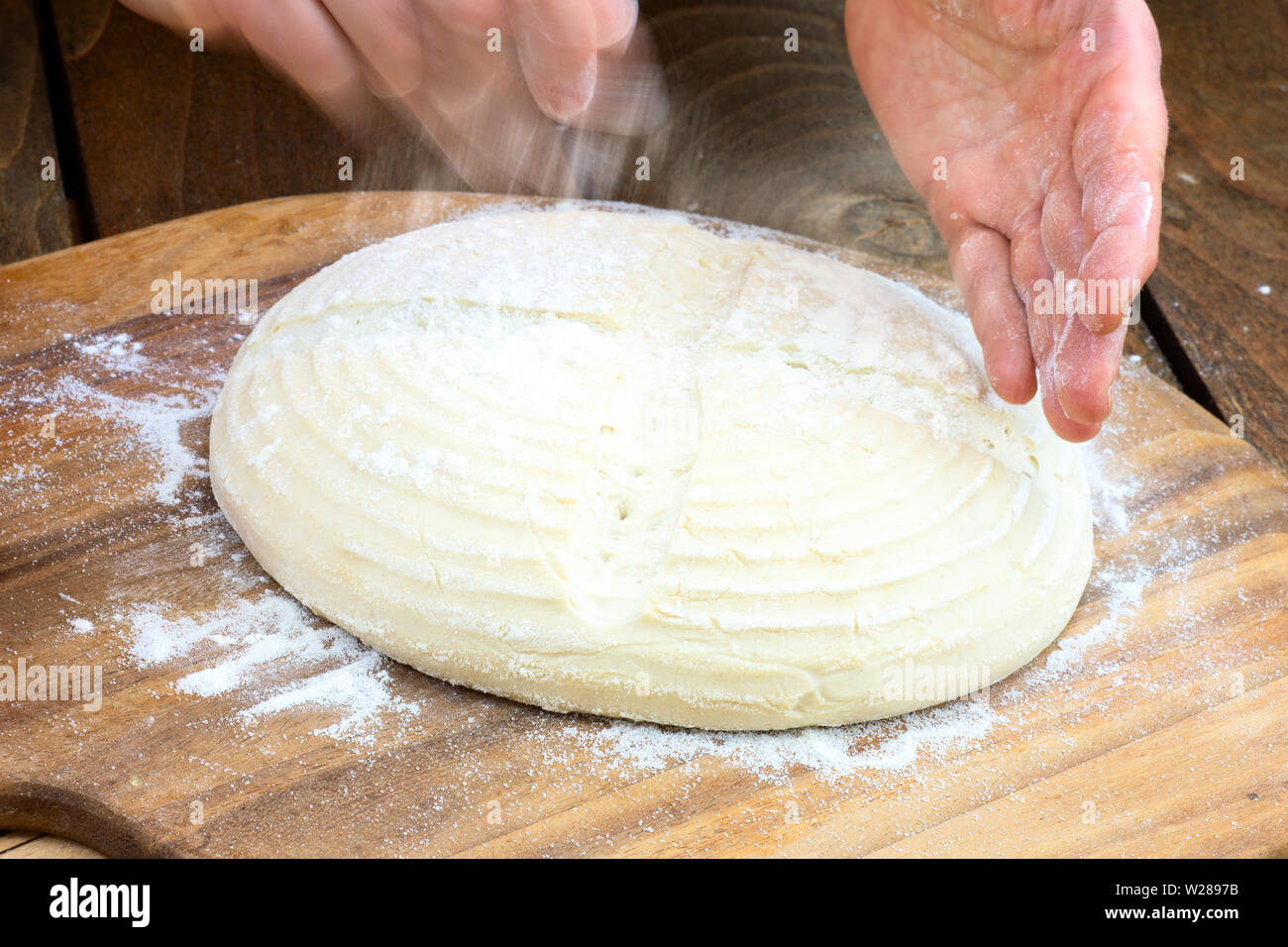 Die Herstellung von Brot: Flouring einer geformten Laib, sitzen auf einer Pizza peel Board ist. Stockfoto