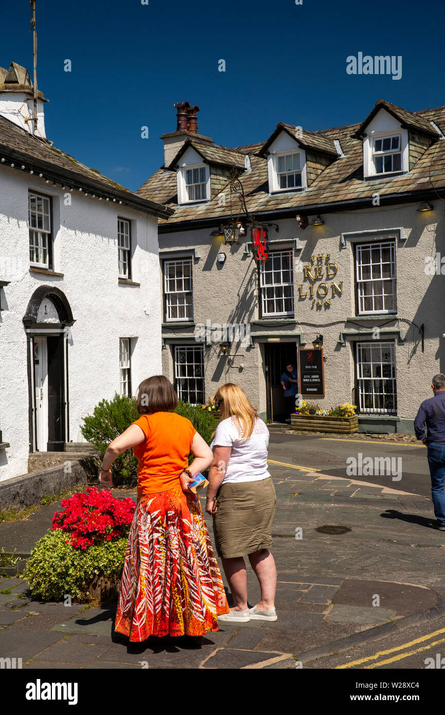UK, Cumbria, Hawkshead, Wordsworth Street, Frauen bewundern floral Pflanzmaschine gegenüber Red Lion Pub Stockfoto