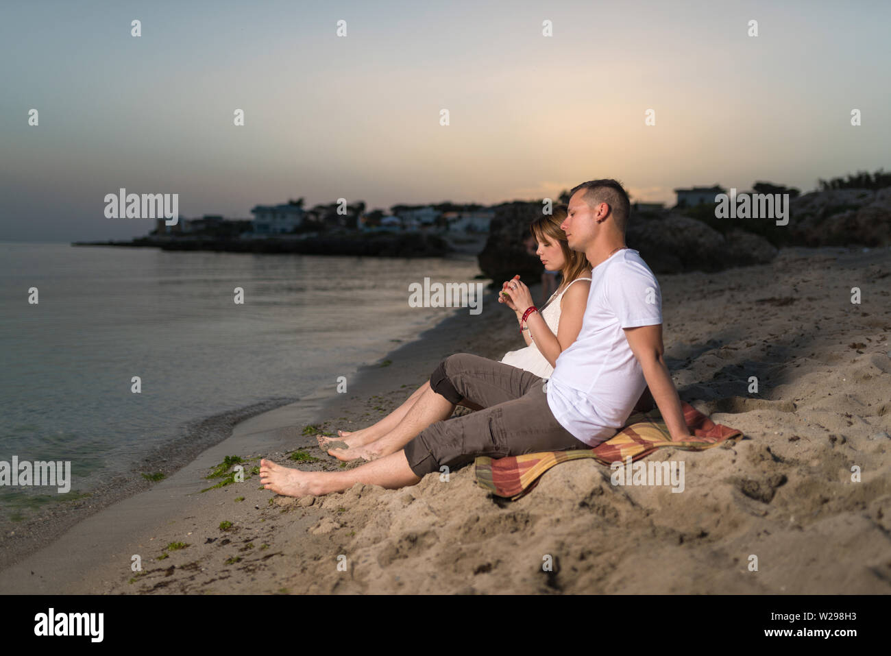 Junge romantische Paar entspannen am Strand zu sitzen und die gemeinsame  Nutzung von Wassermelone am Abend Stockfotografie - Alamy