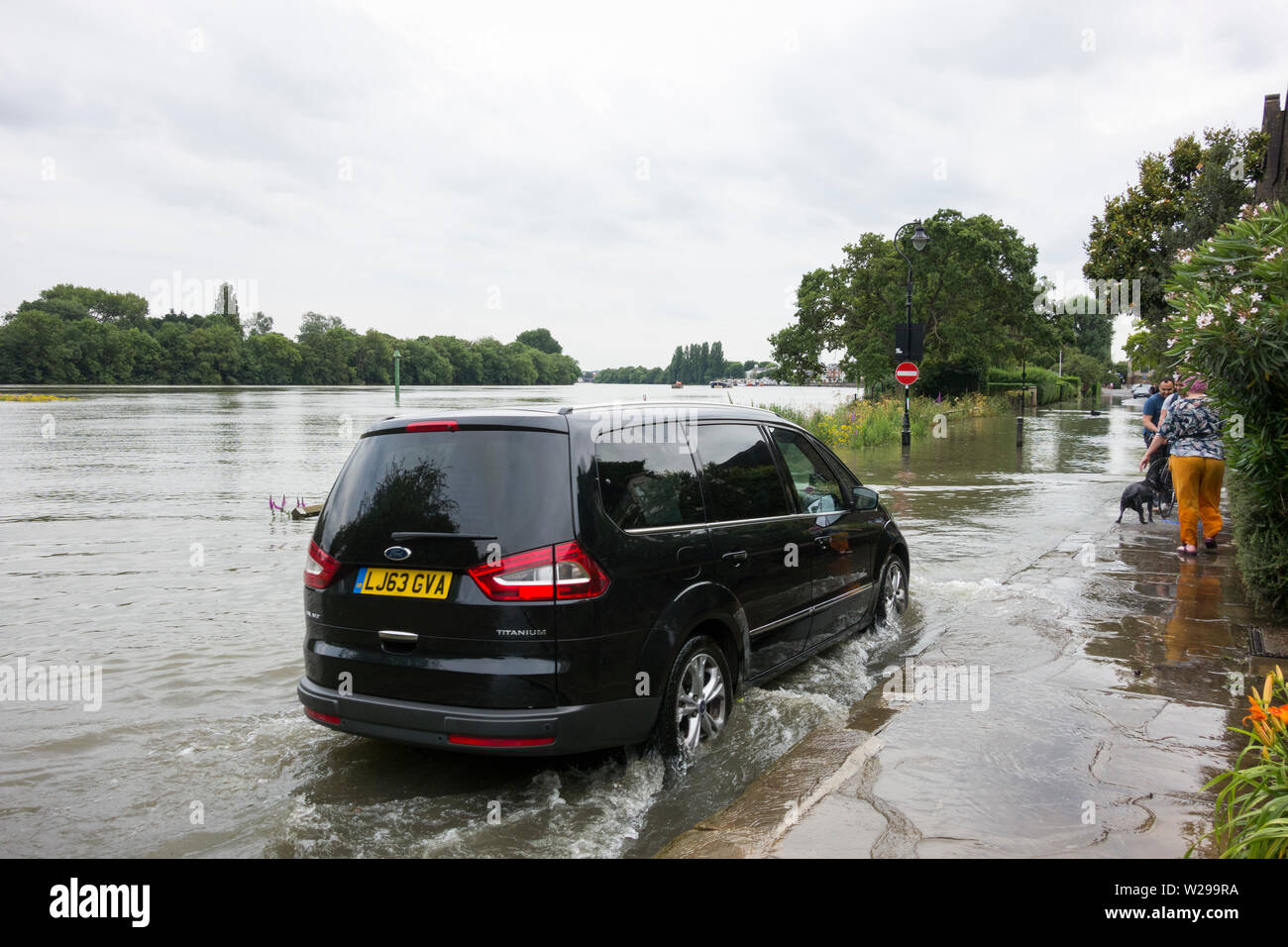 Ein Uber minicab trotzen dem Hochwasser und Überschwemmungen auf der Themse in Chiswick, West London, Großbritannien Stockfoto