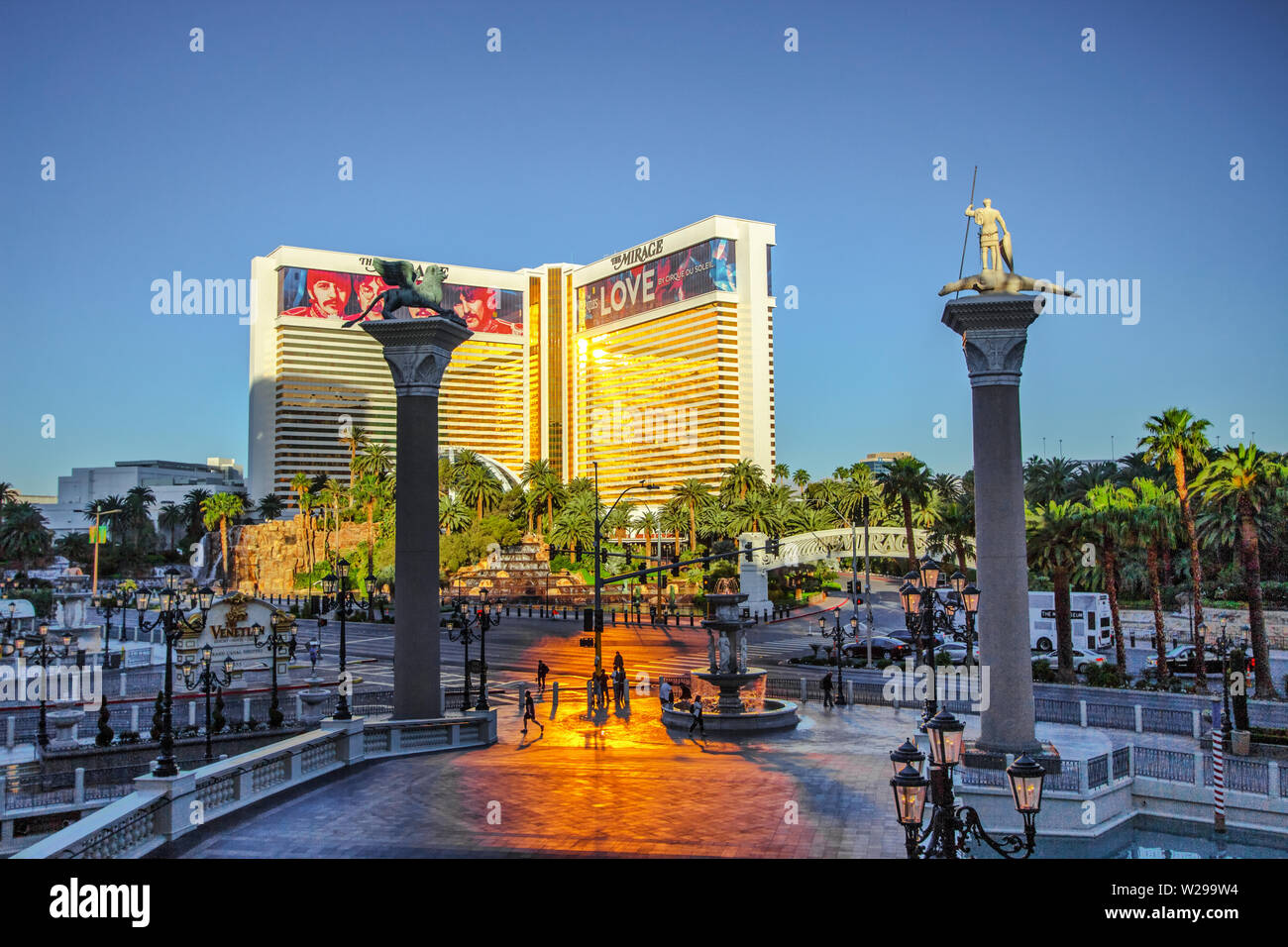 Las Vegas, Nevada, USA - Mai 6, 2019: Touristen Überqueren einer verkehrsreichen Straße auf dem Las Vegas Boulevard bei Sonnenaufgang mit dem Mirage Resort und Casino. Stockfoto