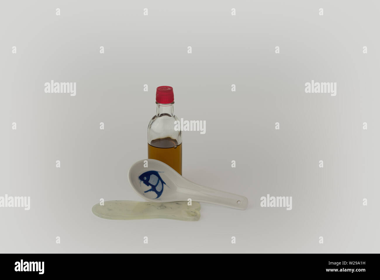 Flasche Massageöl mit Fisch geformt Jade Gua Sha Stein oder Werkzeug und chinesische Suppe Löffel Stockfoto