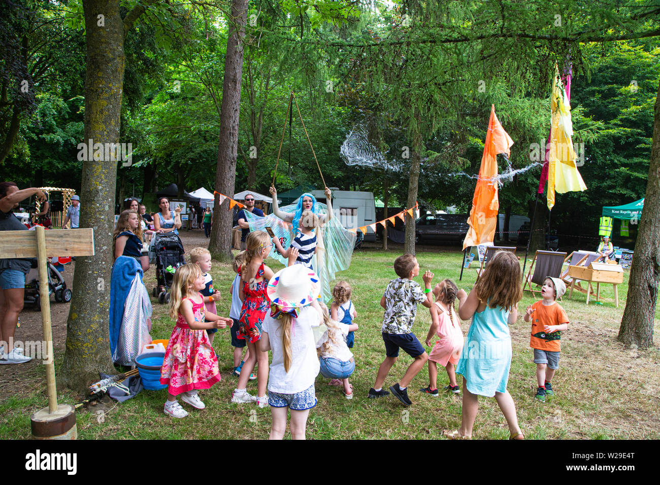 90 Kent County zeigen, Detling, 6. Juli 2019. Einen blauen Haaren Märchen im Wald unterhält Kinder durch Blasen große Blasen.. Stockfoto