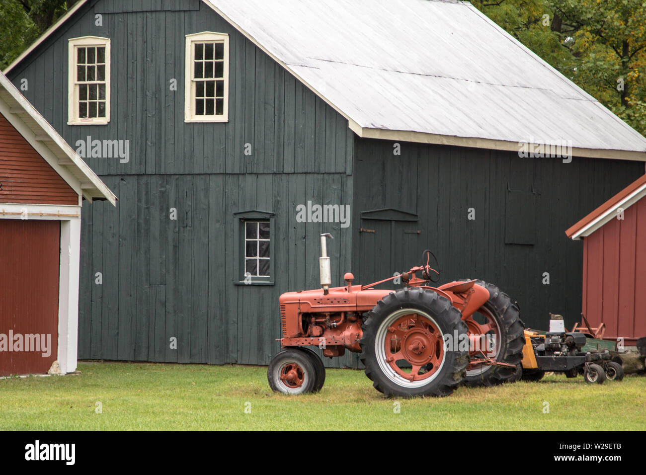 Bauernhintergrund. Roter, antiker Traktor und traditionelle Scheune im amerikanischen Mittleren Westen. Stockfoto