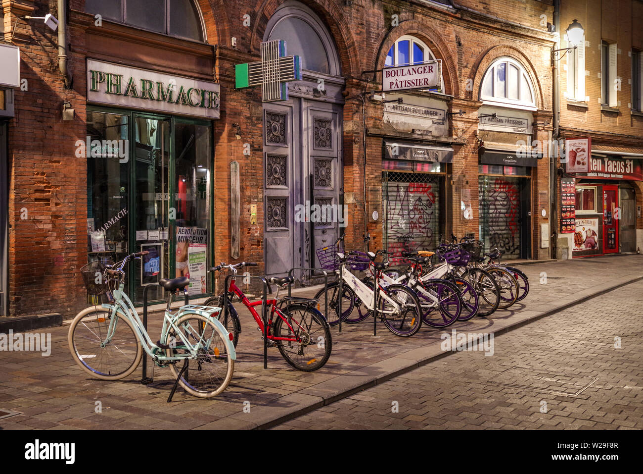 Fahrräder geparkt zusammen eine hübsche historische Straße in Toulouse (Frankreich) bei Nacht Stockfoto
