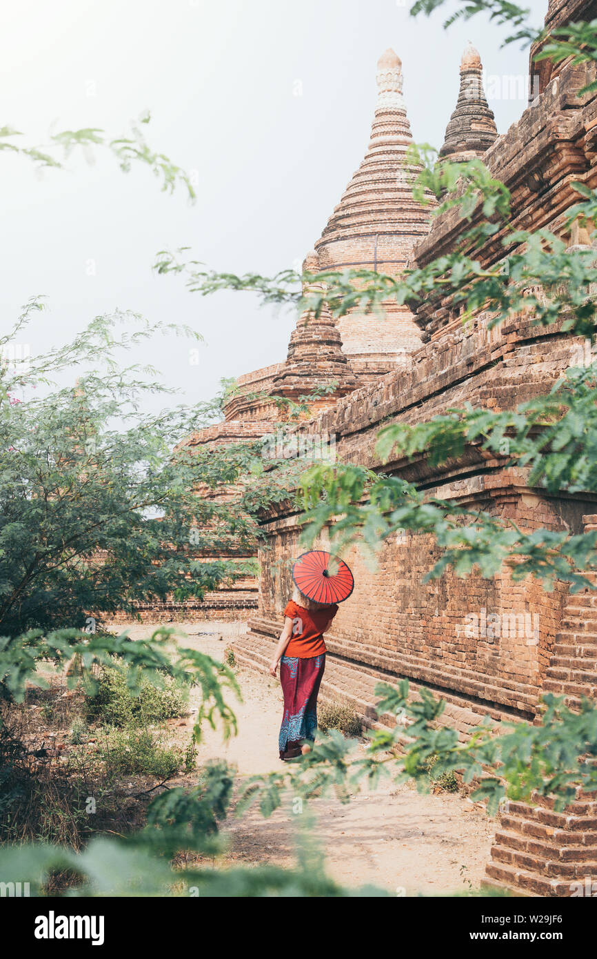 Blond kaukasische Frau mit roten traditionelle Schirmständer unter den Tempeln und Pagoden der alten Bagan in Myanmar Stockfoto
