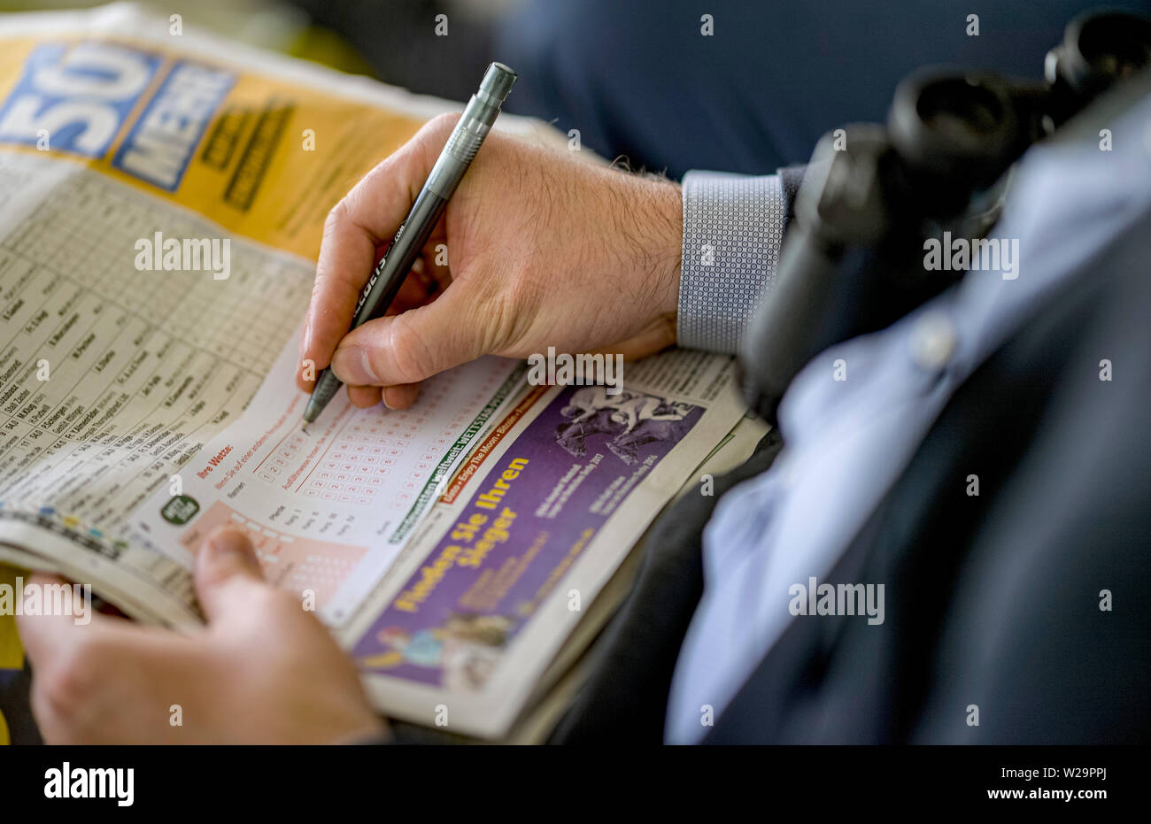 Hamburg, Deutschland. 07 Juli, 2019. Pferderennen: Galopp, Derby Woche Hamburg. Ein Besucher zu Derby Woche füllt ein wettschein. Quelle: Axel Heimken/dpa/Alamy leben Nachrichten Stockfoto