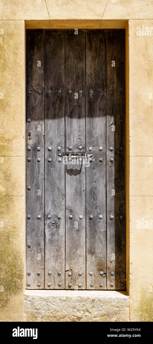 Massive Holztür mit Nieten in der Rahmen von verwitterten Stein, Tür geschlossen - vertikale Ausrichtung im Hochformat Stockfoto