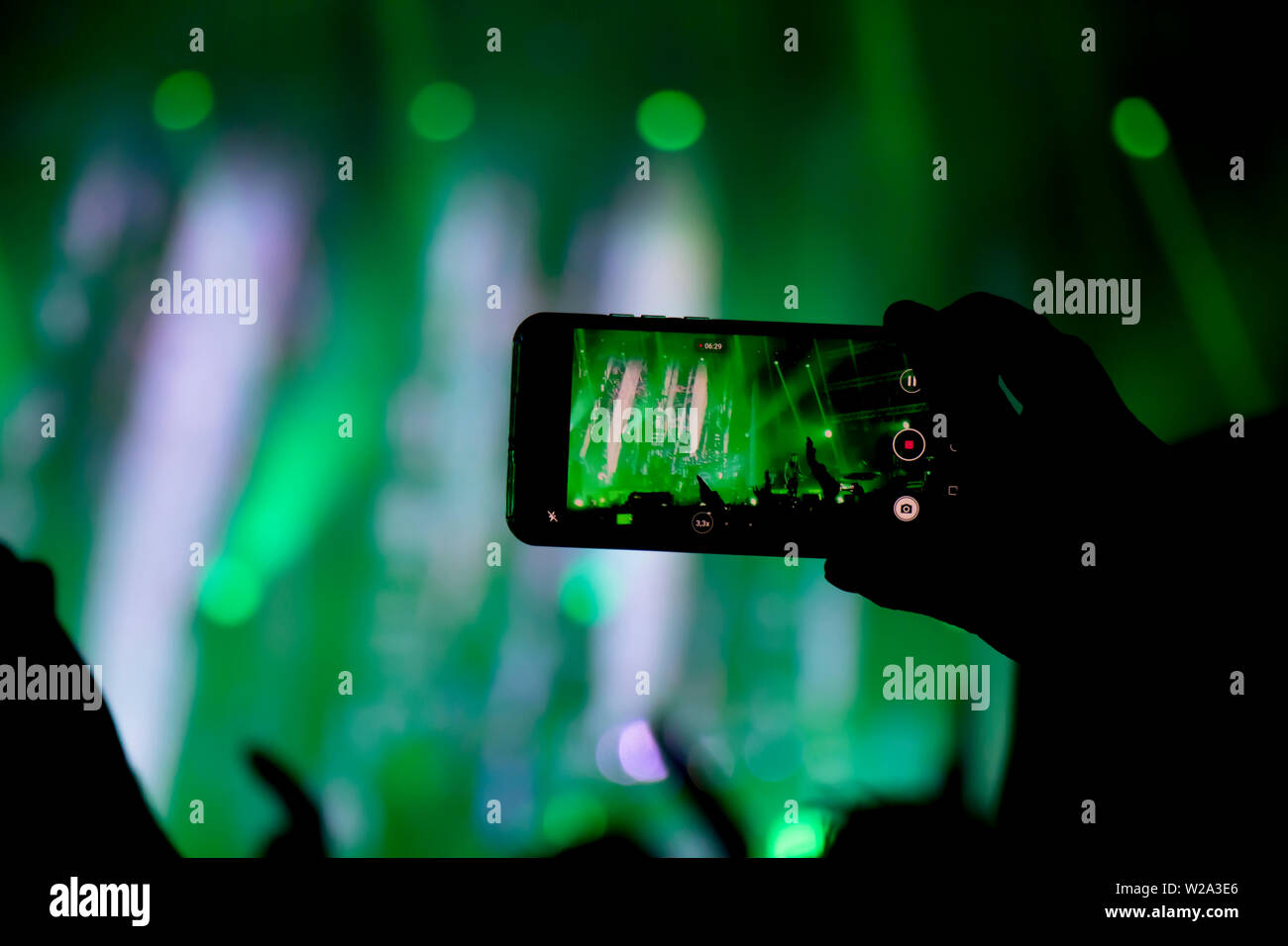 Das Sammeln digitaler Speicher verliert Fähigkeit, Gegenwart, Silhouette eines Mannes schießen die Konzertbühne mit seinem Smart Phone Stockfoto