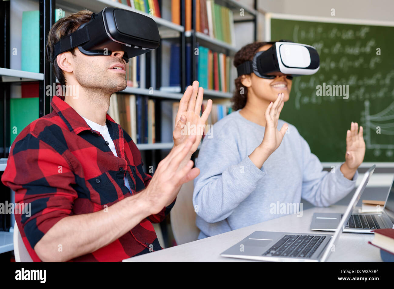 Zwei erstaunt Klassenkameraden im VR-Brille berühren virtuelle Material Stockfoto