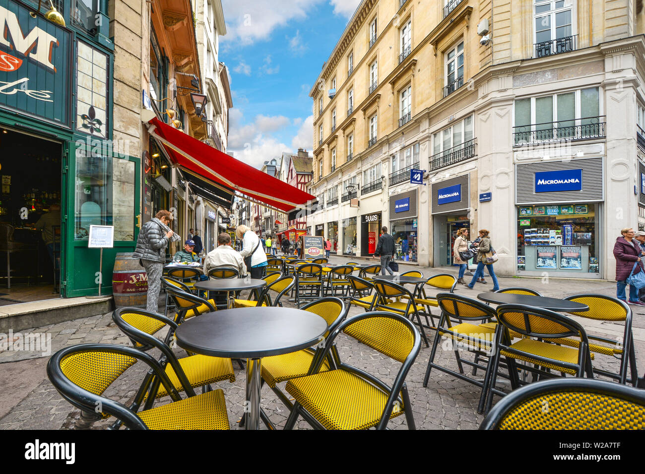 Ein straßencafe mit gelben Stühle auf der touristischen Straße Gros Horloge in der Stadt Rouen in der Normandie Frankreich Stockfoto