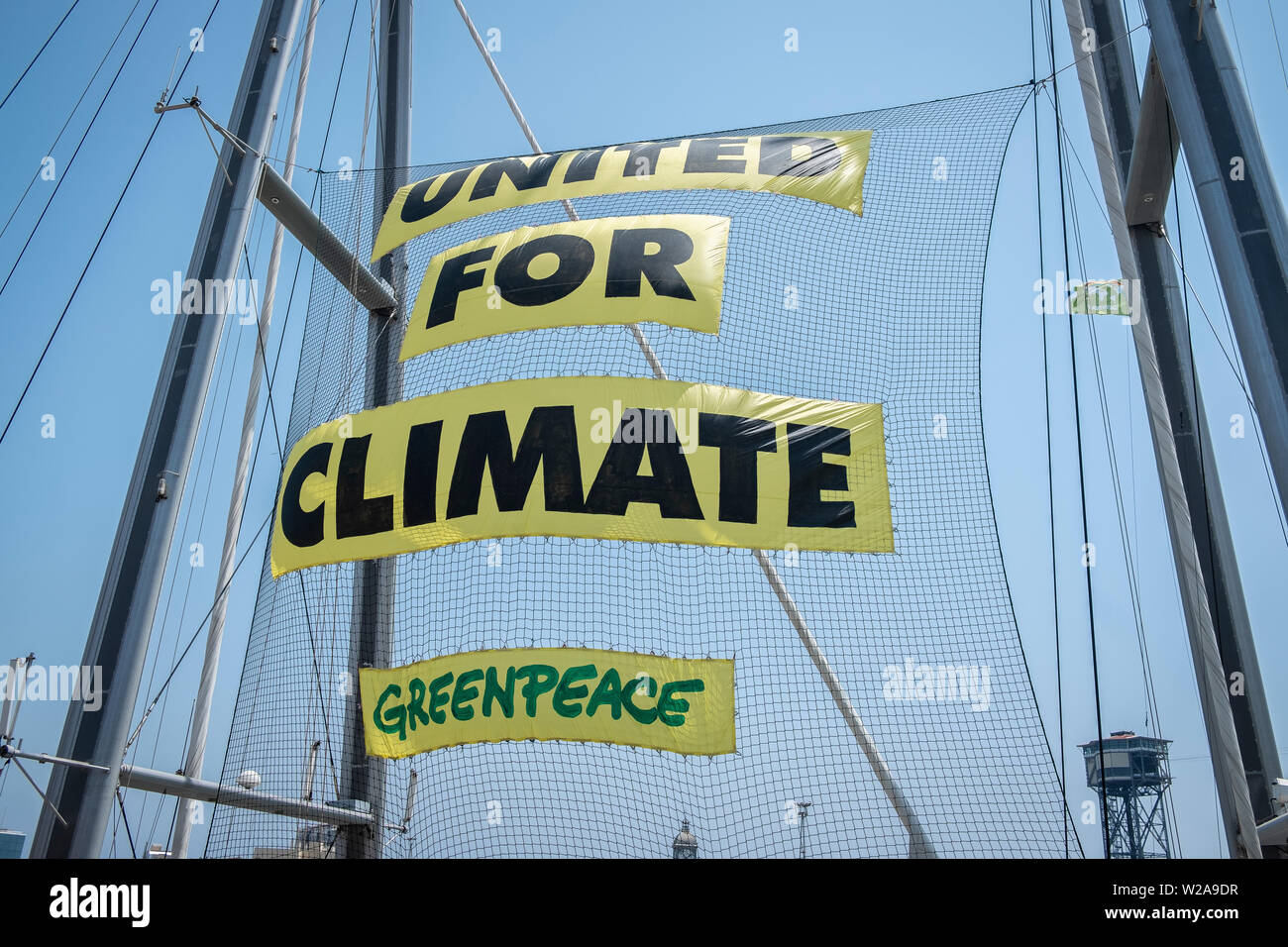 Die Vereinigten für Klima Banner ist Anblick auf die Masten der Rainbow Warrior platziert. Das flaggschiff Rainbow Warrior von Greenpeace in Spanien kommt gegen die Klimakrise zu bekämpfen. Das Segelboot wird in den Häfen von Barcelona, Malaga und Vigo stop dringende Maßnahmen gegen die Klimakrise zu verlangen. Stockfoto