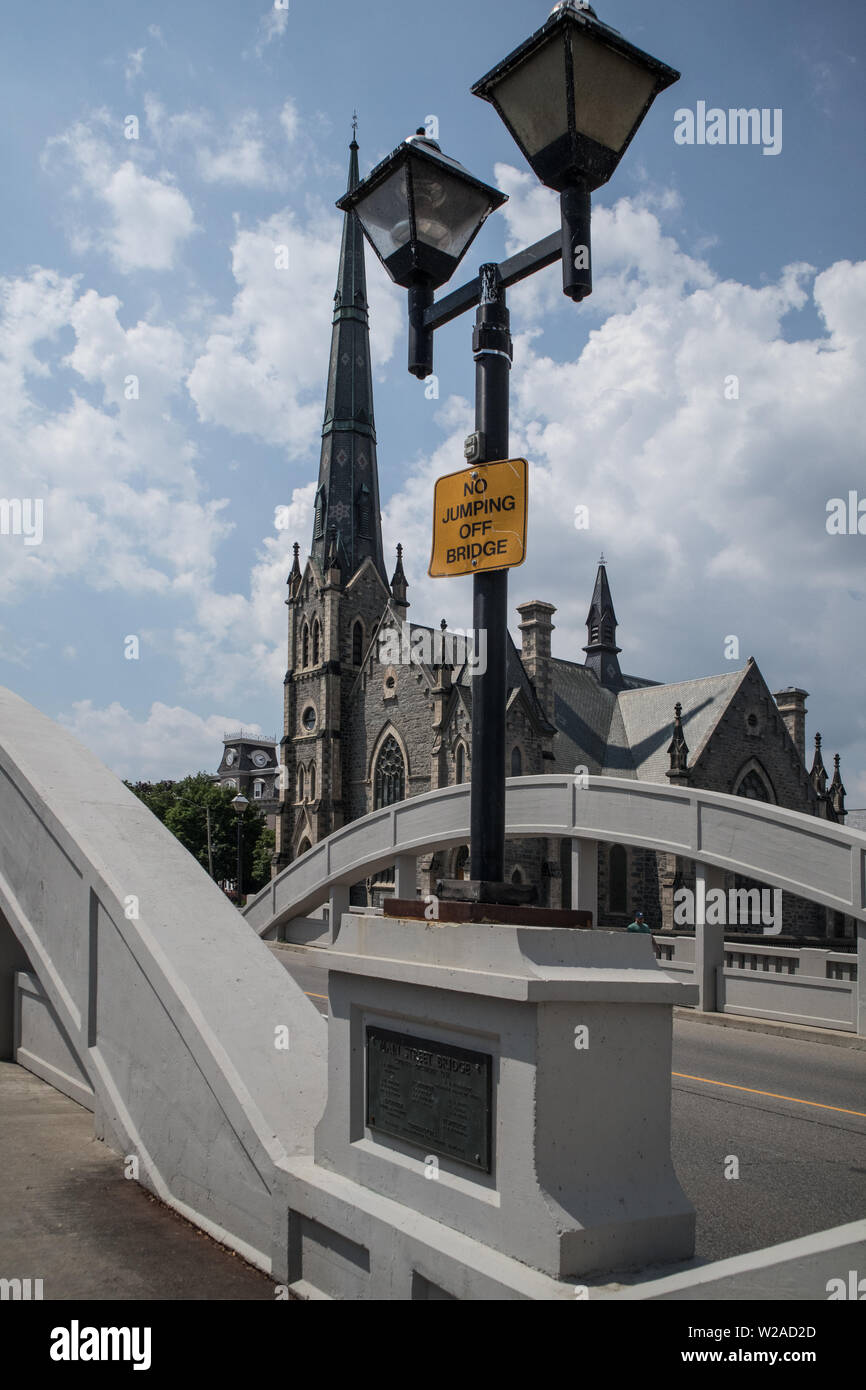 Auf der Laterne auf der Brücke gibt es ein Schreiben, das sagt: No Jumping Off Bridge.. Im Hintergrund sehen wir eine Kirche. Stockfoto