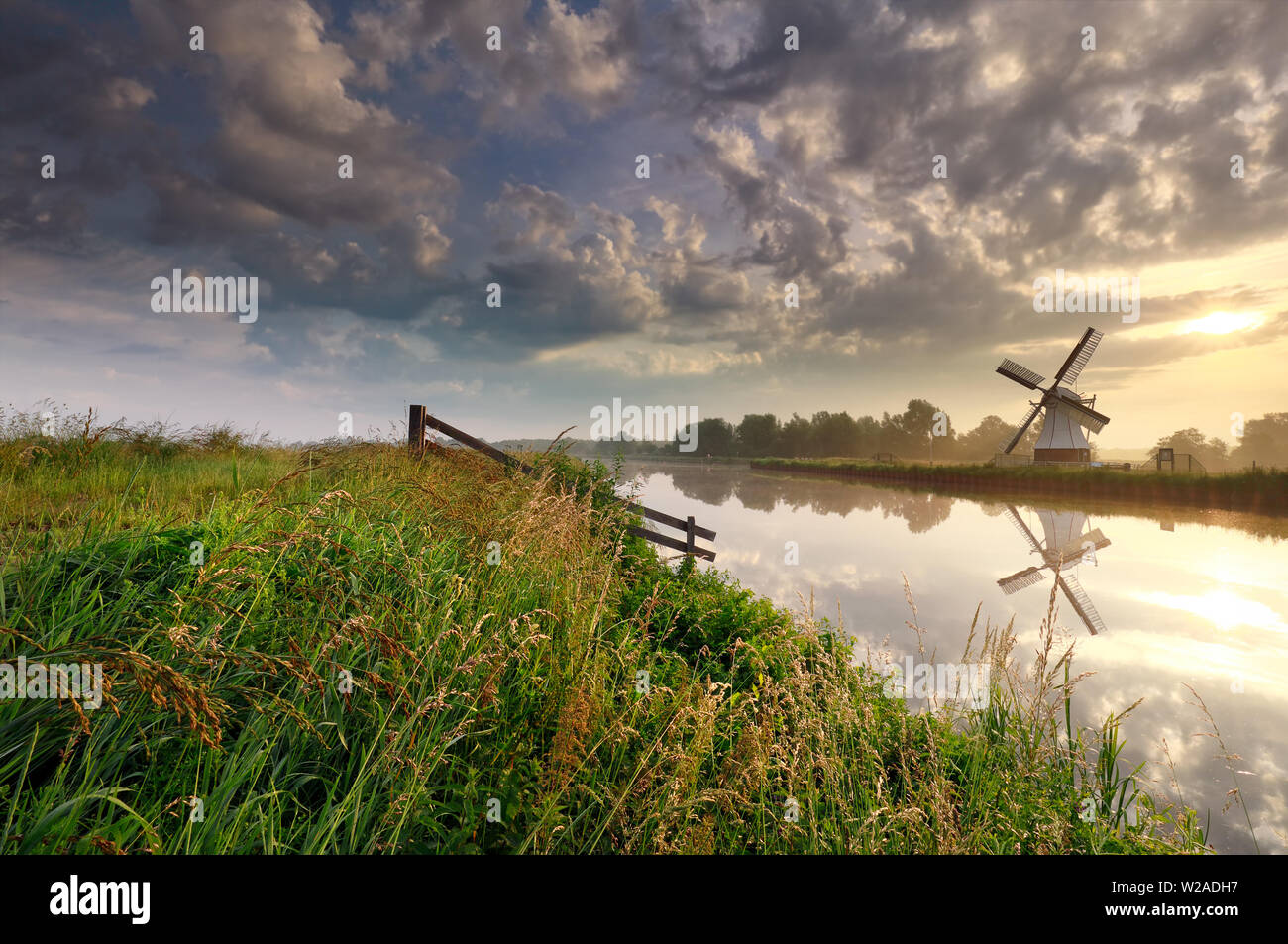 Sonnenaufgang über holländische Windmühle von Fluss, Niederlande Stockfoto