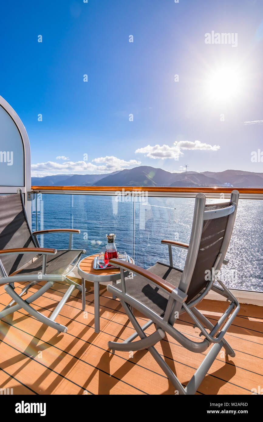 Erfrischendes Getränk auf dem Balkon mit Tisch und Stühlen auf einer Kreuzfahrt Urlaub. Meer Hintergrund. Stockfoto