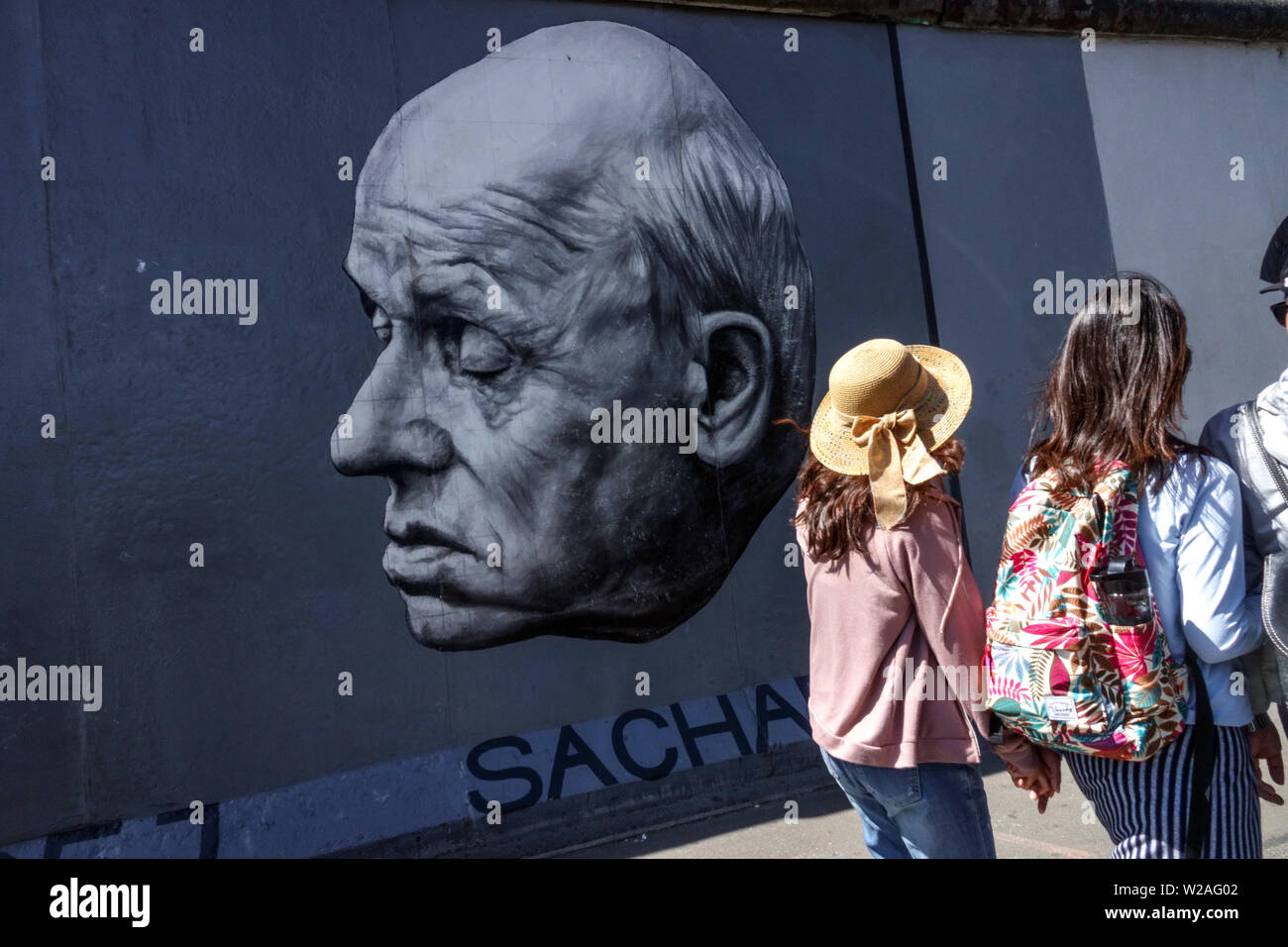 Touristen passieren ein Porträt von Andrei Sacharow. East Side Wall Gallery, Berlin Wall Touristen Deutschland Berlin Wall Graffiti Stockfoto