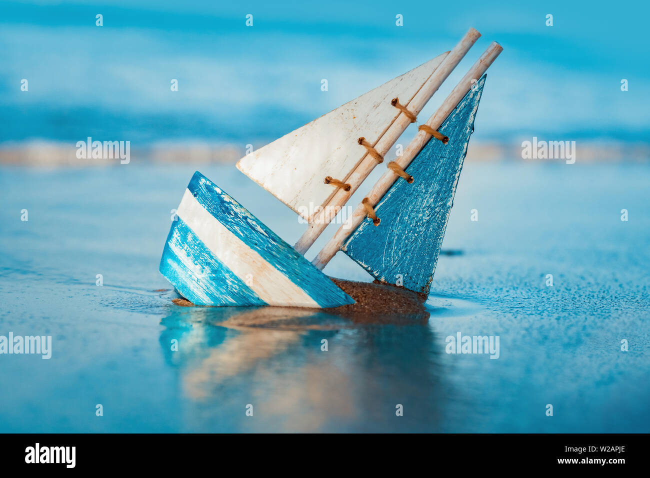 Holzspielzeug Segelboot begraben in Sand in der Nähe der Küste im Sommer. Urlaub und Freizeit Konzept Konzept. Stockfoto