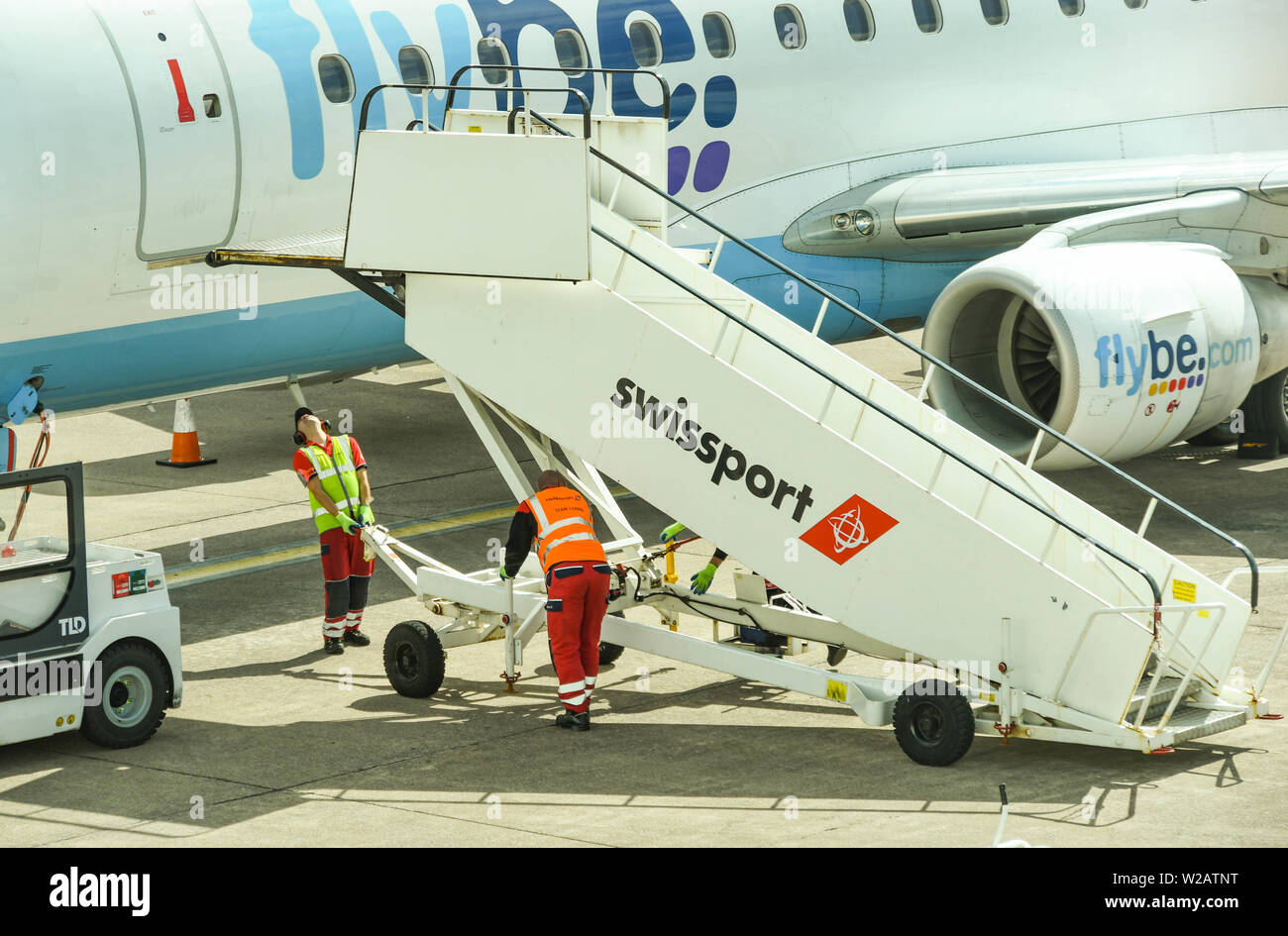 CARDIFF WALES FLUGHAFEN - JUNI 2019: Flughafen Arbeitnehmer, die eine Reihe von Maßnahmen, um die Tür eines Flybe Flugzeug nach der Ankunft in Cardiff. Stockfoto