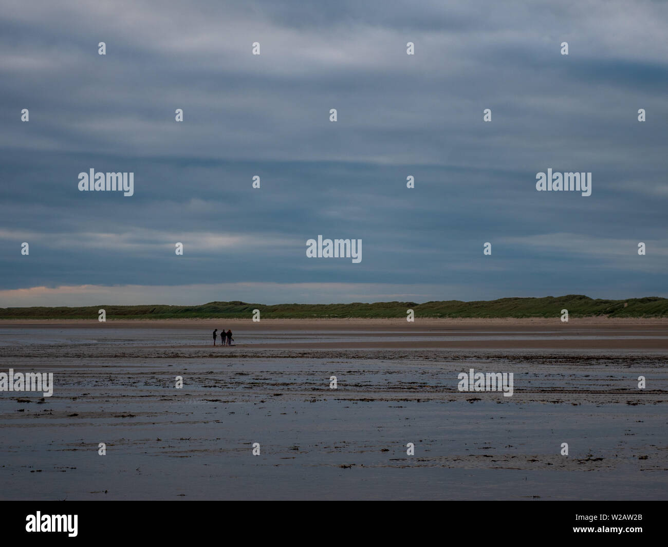 Rhosneigr, Wales, UK - eine ferne Gruppe von Menschen entlang Traeth Cymryan Strand. Stockfoto