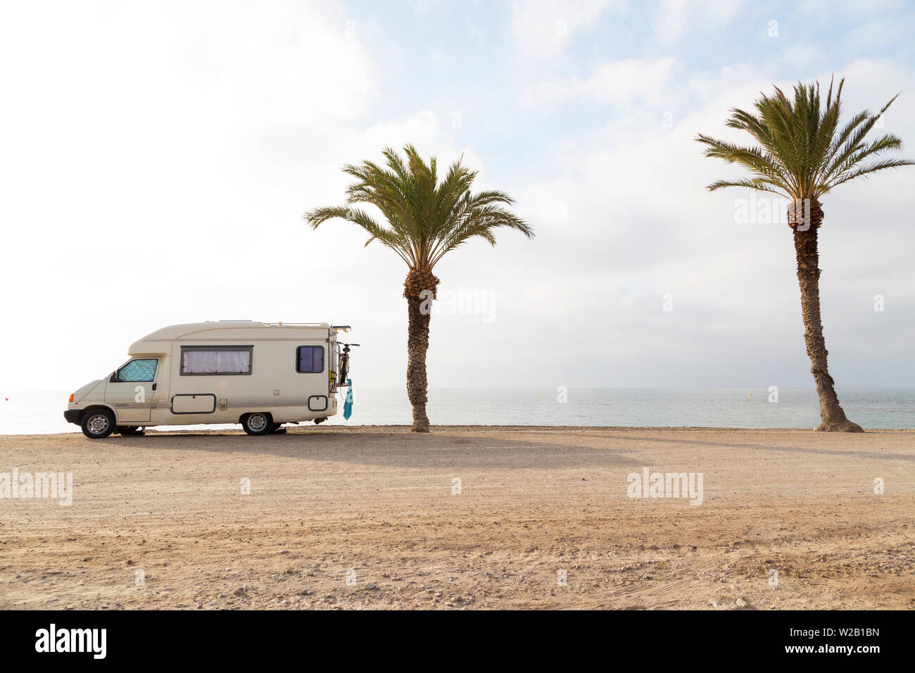 Eine mobile Wohnwagen auf einem Strand mit zwei Palmen mit keine Personen Stockfoto