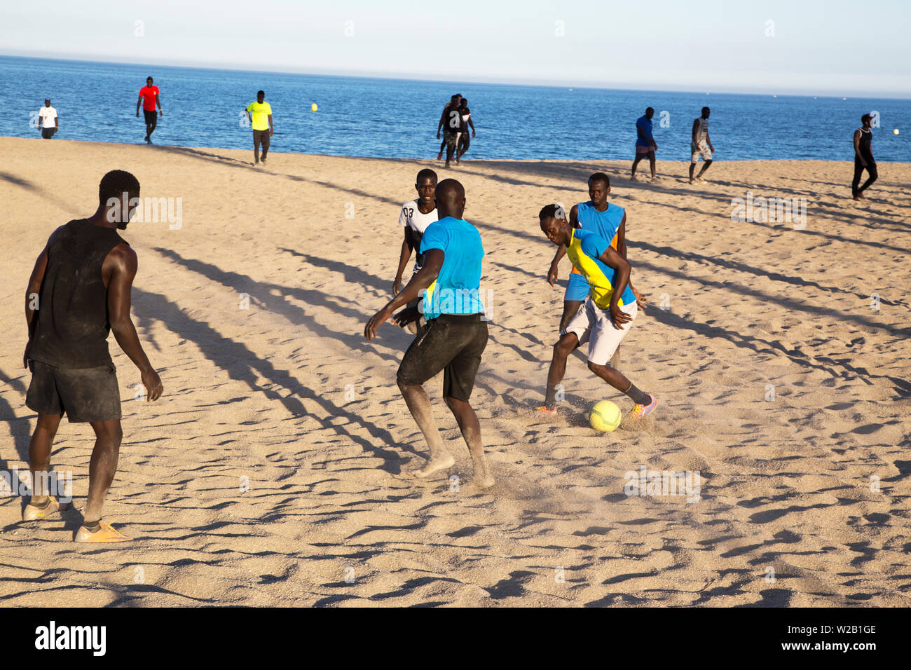 Die afrikanischen Männer am Strand Fußball spielen Stockfoto