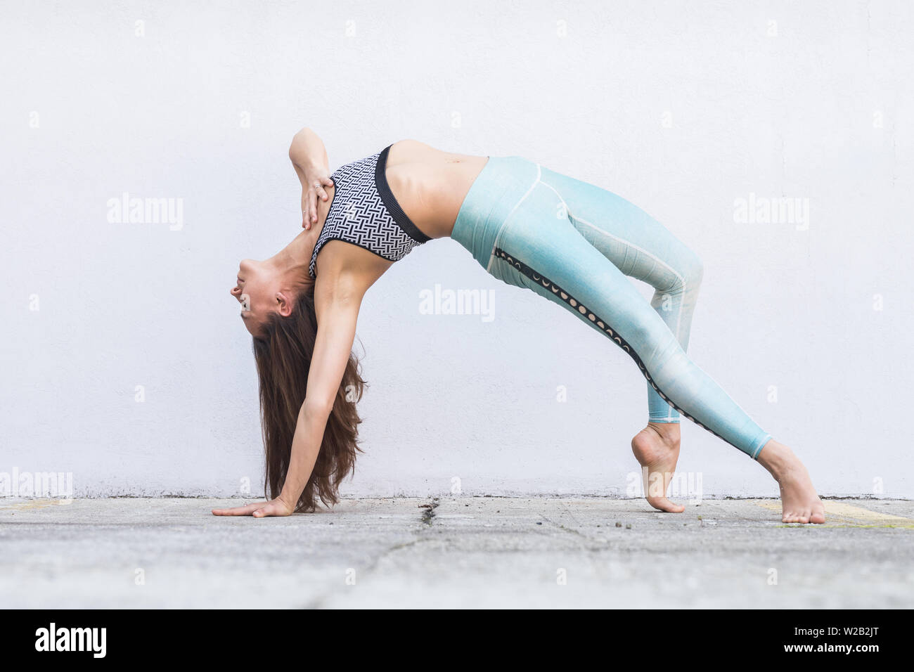 Fit sportlich aktive Mädchen in Mode sportswear Yoga Fitness Übung vor grauen Wand, Outdoor Sport, Urban Style Stockfoto