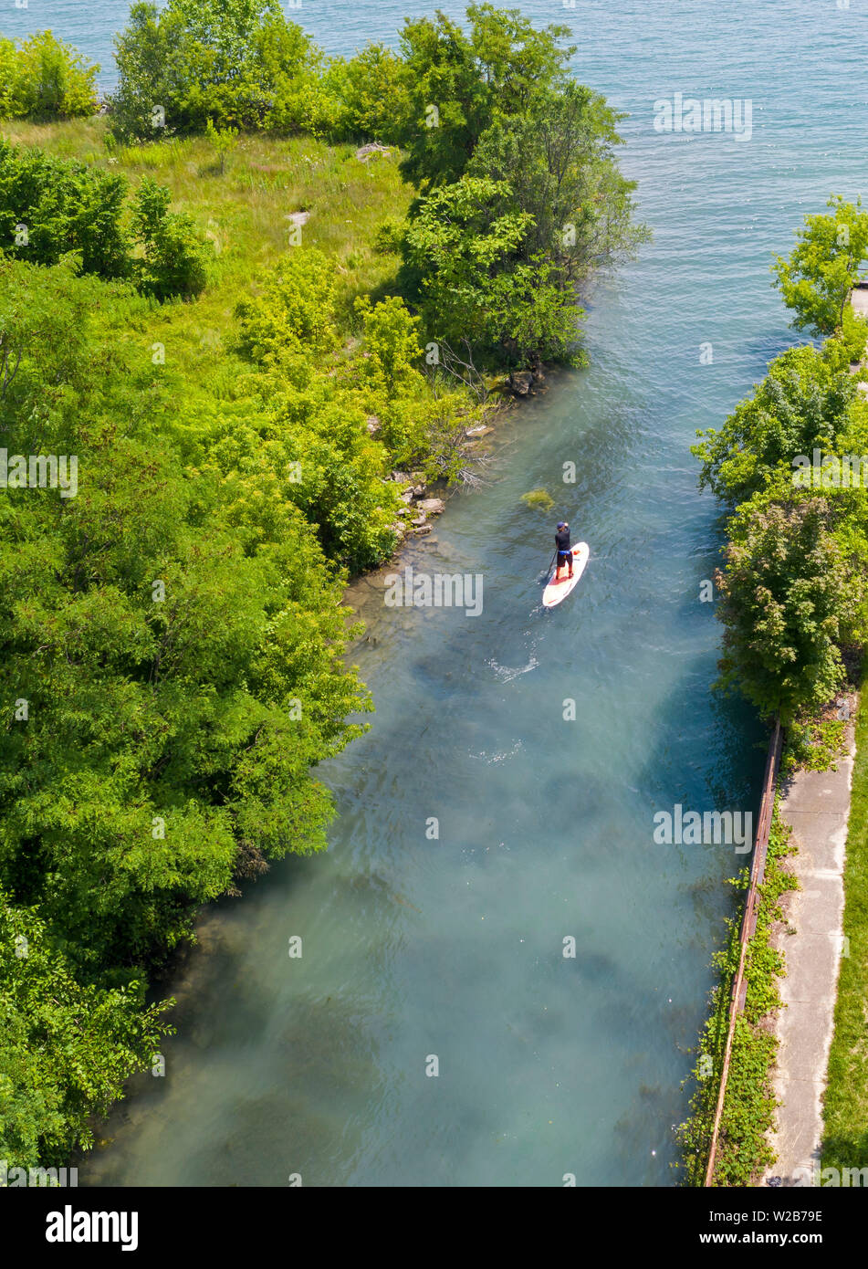Detroit, Michigan - ein Mann auf einem Stand Up Paddle Board paddeln auf einem Kanal in Richtung Detroit River. Stockfoto