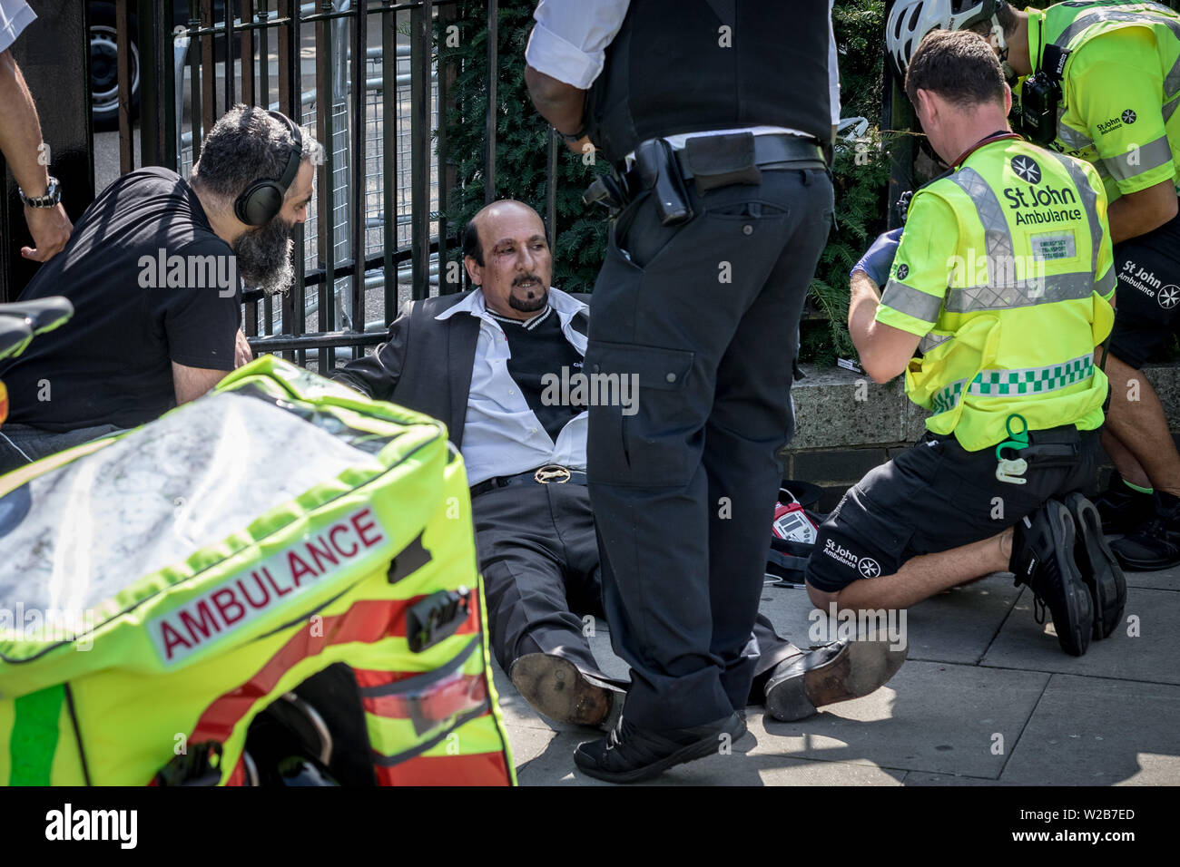 Sanitäter und Polizei kümmern sich um eine verletzte Saudische Prediger nach einem heftigen Auseinandersetzung während einer hitzigen Debatte nahe dem Eingang zum Speaker's Corner. Die Predigt, die Debatten und Predigten an der Speakers' Corner, das öffentliche Sprechen nord-östlichen Ecke des Hyde Park. London, Großbritannien Stockfoto